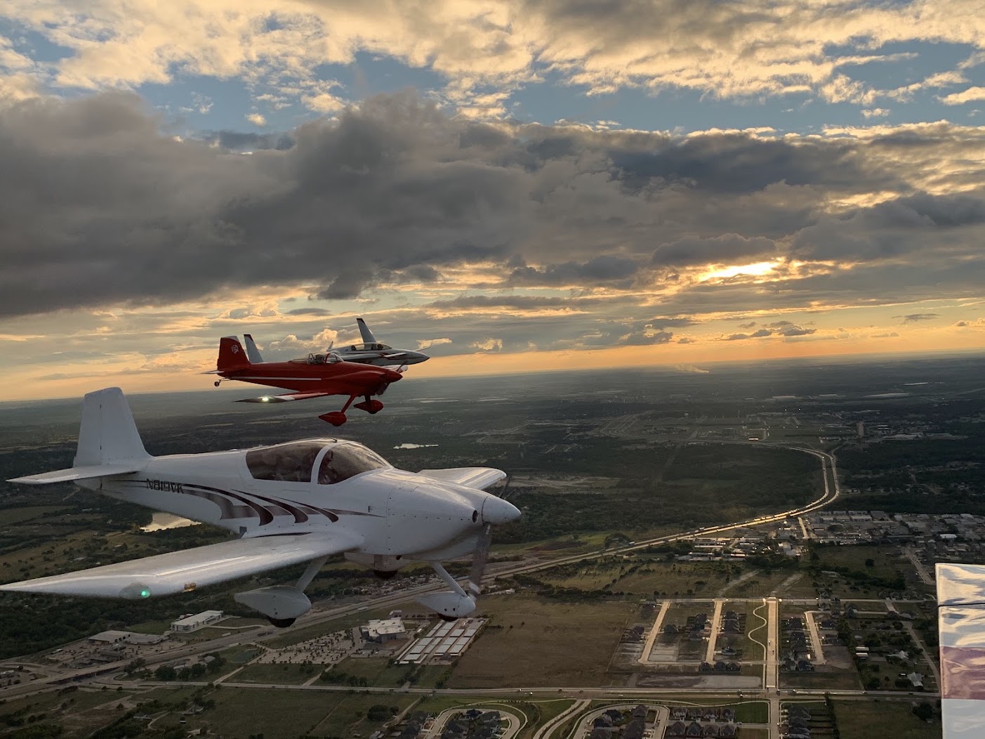 Two aircraft flying in formation over the neighborhood at sunset